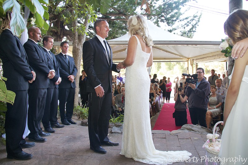 Bride and groom exchange rings in courtyard at Le Kiosk Shelley Beach - wedding photography sydney